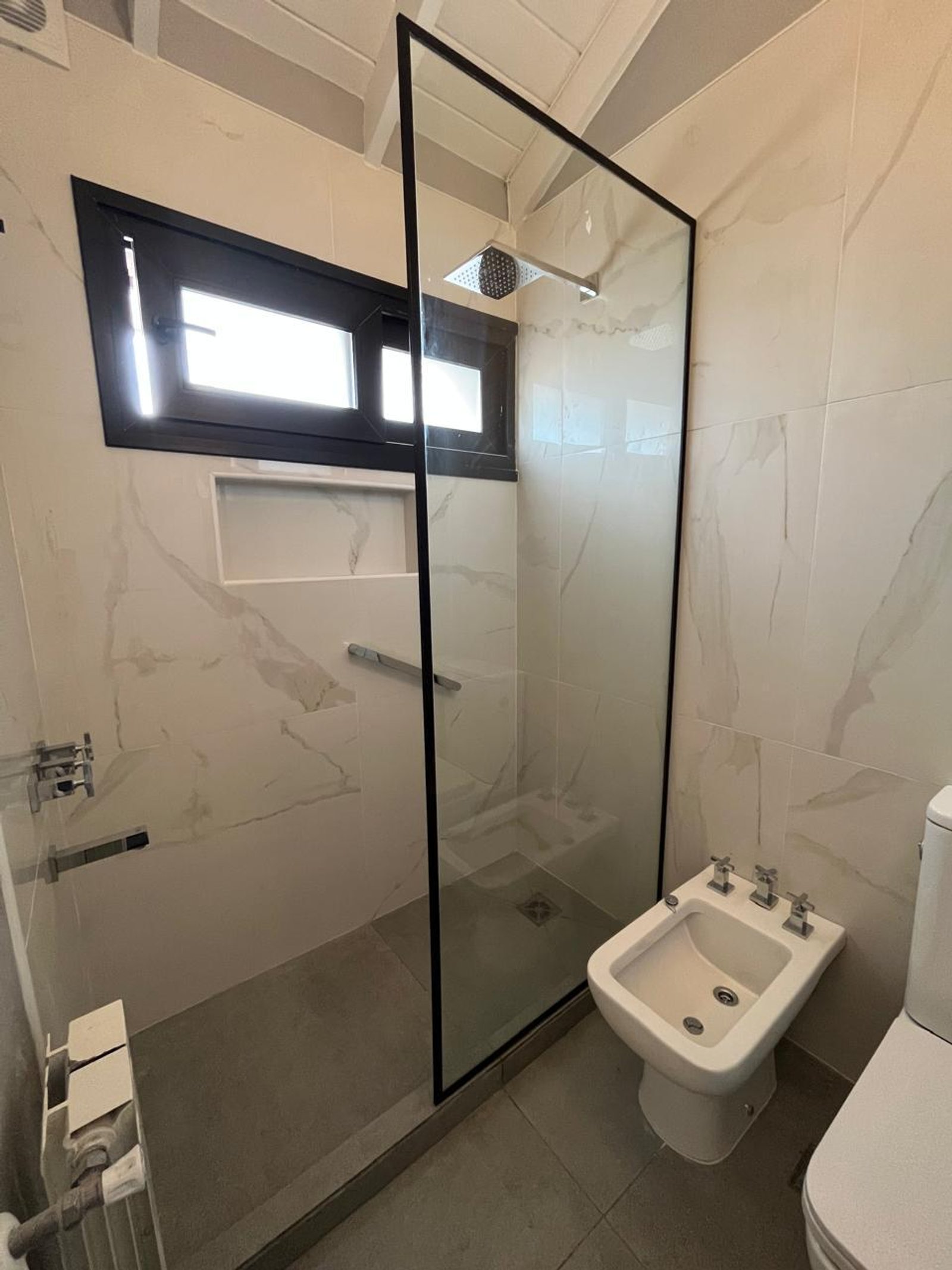 Baño moderno con ducha de vidrio, paredes de mármol y grifería cromada — proyecto Acassuso, por Estudio NET Arquitectura , en Domingo de Acassuso